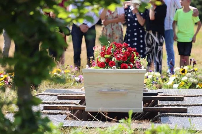 shutterstock_2368329541 White coffin with red flowers at outdoor burial