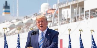 Trump Says Harris Borrowed His Campaign Catchphrase Donald Trump speaking at a podium with American flags and a ship in the background