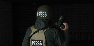 UK Sanctions Backfire? Israel Threatens Intel Freeze Press photographer in helmet and vest holding a camera