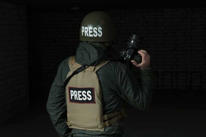 shutterstock_330725141 Press photographer in helmet and vest holding a camera