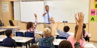 Schools Hid Gender Swaps From Parents Teacher at front of classroom as students raise hands