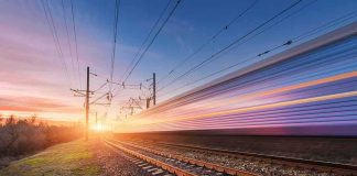 High-speed train passing on railway tracks at sunset