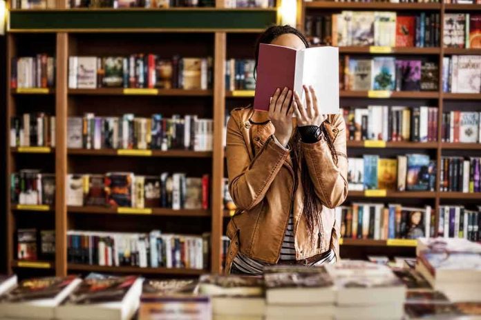 shutterstock_568536961 Person reading a book in a bookstore aisle