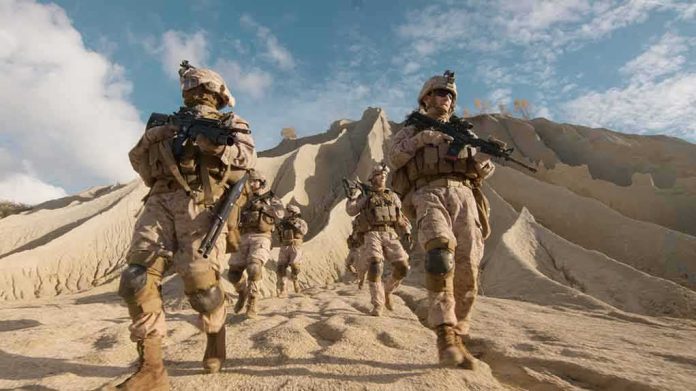 shutterstock_675995335 Soldiers in desert gear patrol a rocky landscape